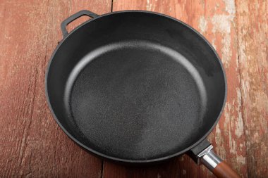 Kırmızı ahşap zemin üzerinde boş demir tava.