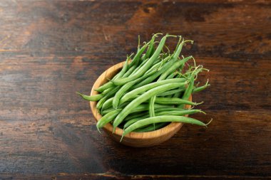 Kavanozda çiğ yeşil kuşkonmaz fasulyesi. Kahverengi ahşap bir masada hasat edin..