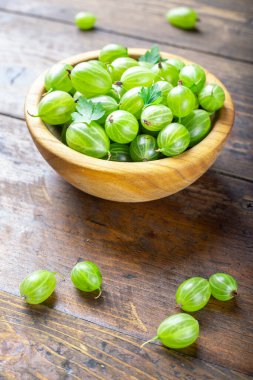 Tahta bir arka planda, ahşap bir tabakta taze yeşil bektaşi üzümü. Yaz vitamin harçları