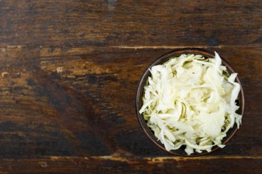 Ahşap arka planda bir kasede doğranmış lahana. Sebze, malzeme ve zımba. Sağlıklı yemek..