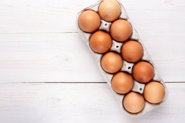 Ahşap bir arka planda karton tepside kırmızı tavuk yumurtası. tex için yer