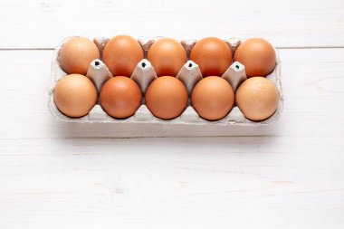 Ahşap bir arka planda karton tepside kırmızı tavuk yumurtası. tex için yer