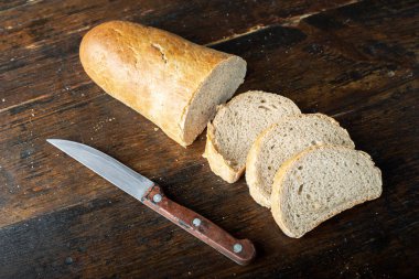 Kahverengi ahşap bir masada taze dilimlenmiş beyaz buğday ekmeği. tex için yer