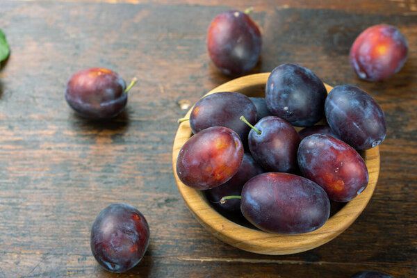 Свежие сливы в деревянной чаше. Сбор урожая. Вкусные фрукты.