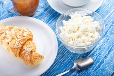 Beyaz tabakta kruvasan ve süzme peynirli hamur işi kahvaltı..