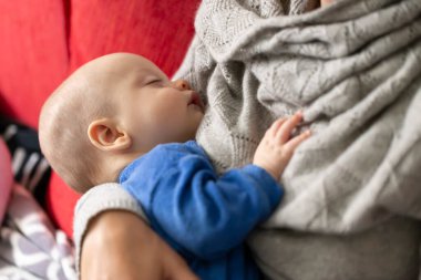 Mavi pijamalı güzel bebek annenin kollarında uyuyor.