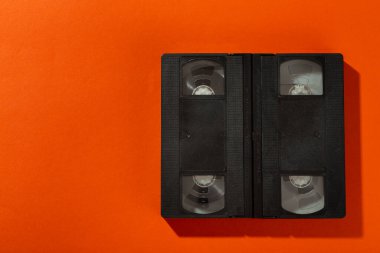 Turuncu arka planda kapağı olmayan bir video kaset. Üst görünüm.