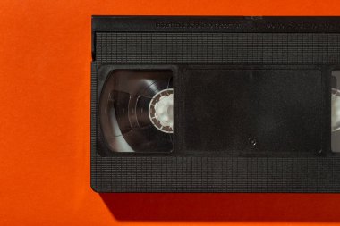 Turuncu arka planda kapağı olmayan bir video kaset. Üst görünüm.