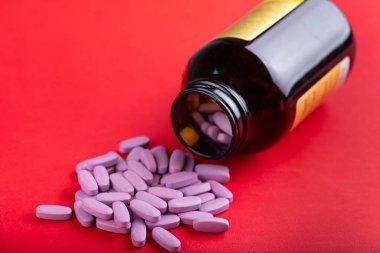 Oval pembe haplar parlak kırmızı arka plandaki bir kavanozdan dökülür. tex için boşluk