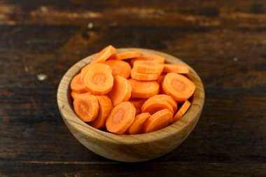 Ahşap arka planda bir kasede dilimlenmiş havuç. Sebze, malzeme ve zımba. Sağlıklı yemek..