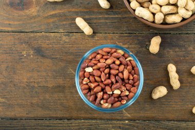 Cam bir kasede soyulmuş fıstık ve ahşap bir masada soyulmamış. Üst Manzara. Metin için boşluk.