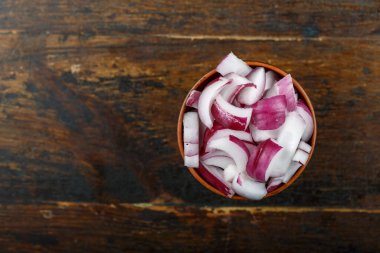 Ahşap arka planda bir kasede dilimlenmiş kırmızı soğan. Sebze, malzeme ve zımba. Sağlıklı yemek..