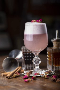 Kuru güllerle süslenmiş köpüklü pembe alkollü kokteyl. Ahşap arka planda iç. Barmen özellikleri yan yana gelir. Büyük bir şehirde gece hayatı