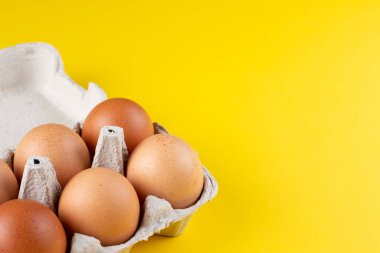 Açık yumurta kutusundaki tavuk yumurtaları sarıya izole edilmiş. Kopyalama alanı olan üst görünüm. Doğal sağlıklı gıda ve organik tarım kavramı. 