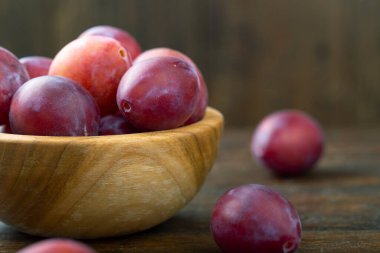 Masadaki ahşap kasede olgun erikler. Hasat mevsimi.