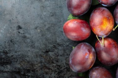 Koyu demir zemin üzerinde olgun erikler. Hasat mevsimi. Mesaj için yer var. Üst görünüm.