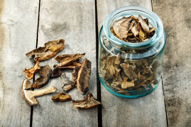 Ahşap bir masada cam bir kavanozda kurutulmuş mantar. Mantar mevsimi.