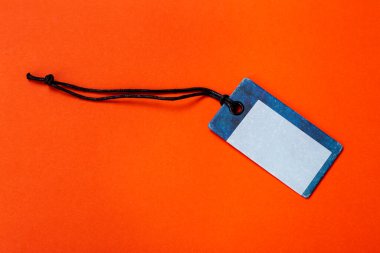 Ürüne asılmak için boş etiket bağlandı. Turuncu arkaplanda indirimli fiyat veya indirim izolasyonu.