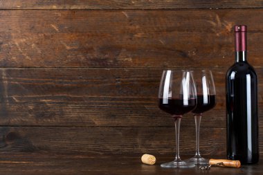 Bir şişe şarap ve iki bardak. Yakınlarda tirbuşon ve mantar var. Metin için Soace.