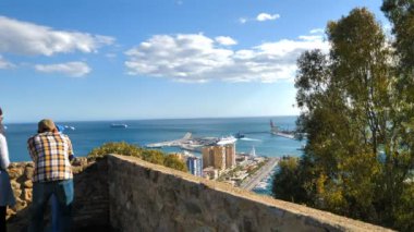 Günbatımında turistler görüş açısında. Şehrin gökyüzü manzarası, liman ve yolcu gemileri. Malaga, İspanya.