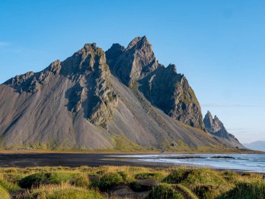 Güneşli bir günde Stokksnes 'teki siyah kumlu sahilin destansı manzarası. Arka planda Vestrahorn Dağı var. Doğa ve ekoloji kavramı.