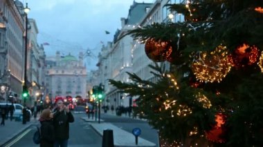 Çift, Londra sokaklarındaki bir Noel ağacına fotoğraf çekiyor.