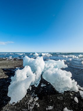 Kara kumdaki büyük buz, İzlanda 'nın en turistik yerlerinden biri olan elmas plajındaki Jokulsarlon buzulunun bir parçası..