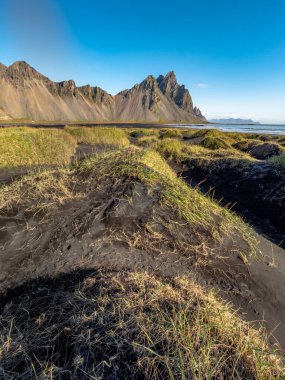 Güneşli bir günde Stokksnes 'teki siyah kumlu sahilin destansı manzarası. Arka planda Vestrahorn Dağı var. Doğa ve ekoloji kavramı.