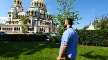 Genç beyaz adam, Bulgaristan 'ın Sofya kentindeki Alexander Nevsky katedraline resim çekiyor. Yalnız gezgin konsepti. Sinematik hareket.