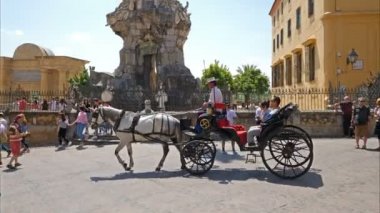 Cordoba, İspanya. Haziran 2018. Aziz Raphael Başmelek Anıtı 'nın yanındaki at arabasında turistler