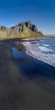 Epic view landscape of the black sand beach in Stokksnes on a sunny day. Vestrahorn mountain in the background. Nature and ecology concept background. clipart