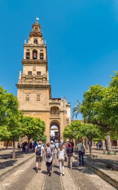 Cordoba, İspanya. Mayıs 2018. Cami-Katedral 'in yanındaki portakal bahçesi Patio de los naranjos' u ziyaret eden turistler. Torre del campanarios (Çan kulesi) arka planda.