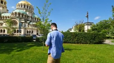 Genç beyaz adam, Bulgaristan 'ın Sofya kentindeki Alexander Nevsky katedraline resim çekiyor. Yalnız gezgin konsepti. Sinematik hareket.