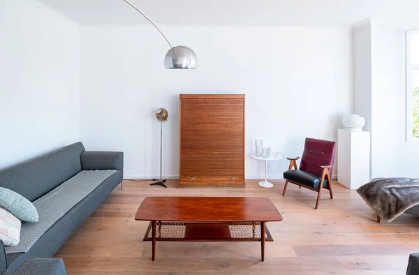 木製の床 大きなソファ 木製のテーブル モダンなランプ 大きな窓 レトロな家具付きの最小限のスタイリッシュな明るいリビングルーム ヴィンテージ装飾が施された広々とした北欧スタイルのインテリア — ストック写真