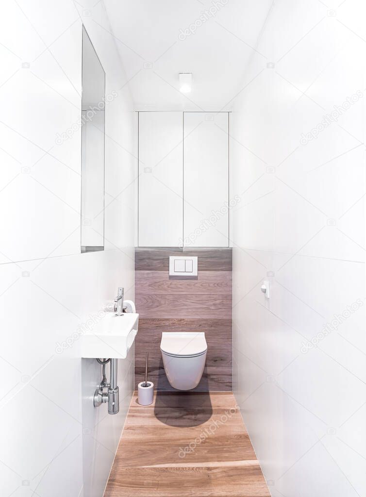 Small bathroom interior with white tiles and fake wooden floor. Original designed toilet space with modern minimal pieces.