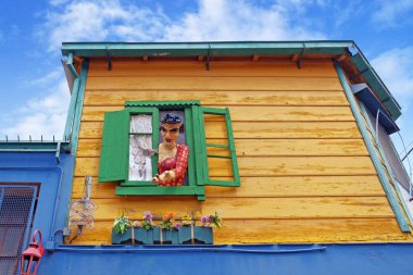 Mavi bir yaz gökyüzüne karşı Buenos Aires ünlü Arjantin bölgesi La Boca sarı bir evin yeşil penceresinde renkli heykel.