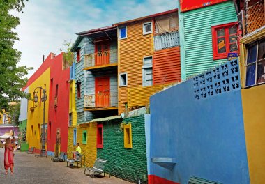 Buenos Aires'te Arjantin'in La Boca semtindeki renkli binaların önünde mavi bir gökyüzüyle bir yaz günü bir çocuk fotoğrafı çektiren kadın.