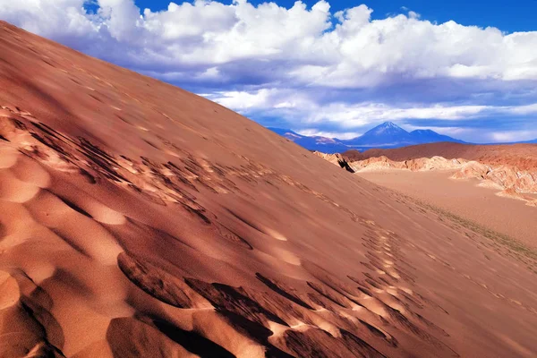 Blick auf Sanddünen und felsige Hügel im Marstal bei San Pedro de Atacama vor blauem Himmel über Vulkanen. — Stockfoto
