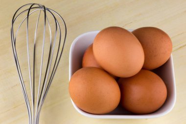 Çırpma teli ve ahşap masa üstü üzerinde yumurta