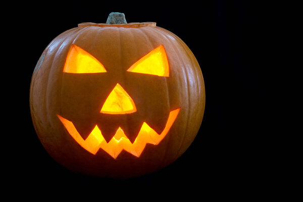 Иллюминированная на Хэллоуин тыква на черном фоне
