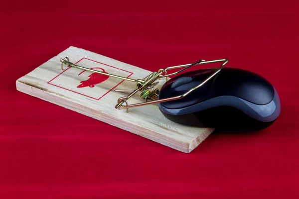 An old fashioned wooden rodent trap with computer mouse on a red background