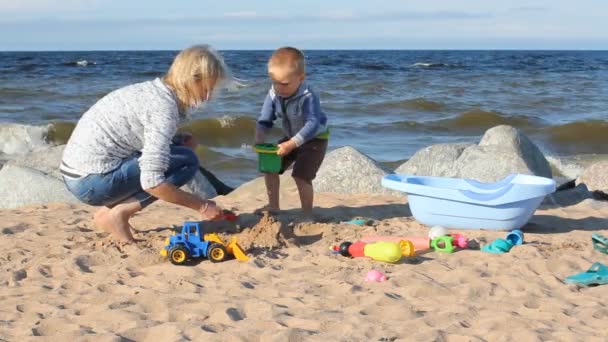 母亲和孩子在海边玩沙子 自然的家庭度假 一个年轻的女人 她的儿子在海边玩沙滩 — 图库视频影像