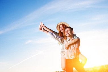 Mutlu kız arkadaşıyla yükseltilmiş el piggybacking genç adam. Neşeli severler rüya.