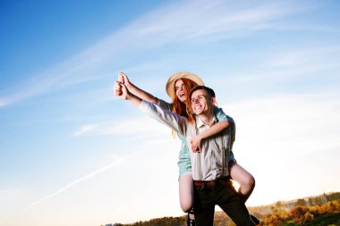 Mutlu kız arkadaşıyla yükseltilmiş el piggybacking genç adam. Neşeli severler rüya.