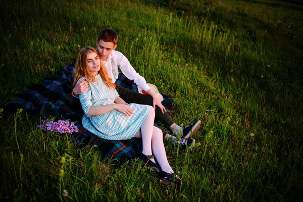 Genç çift ekose parkta oturan ve gün batımında bak.