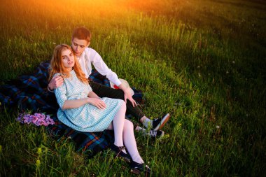 Genç çift ekose parkta oturan ve gün batımında bak.