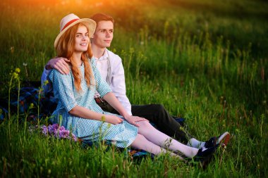 Genç çift ekose parkta oturan ve gün batımında bak.