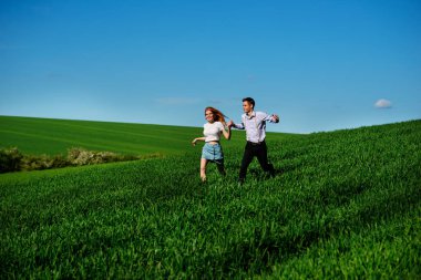 mutlu aşıklar çayır çimen yeşil ve mavi gökyüzü ile çalışan.