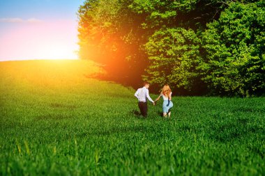 Mutlu aşıklar çayır yeşil çim ve arkasından mavi gökyüzü ile çalışan.