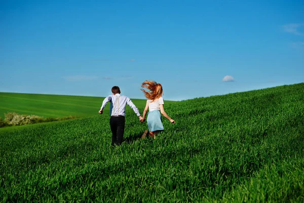 Молодые Счастливые Влюбленные Бегут Лугу Зеленой Травой Голубым Небом Спины — стоковое фото